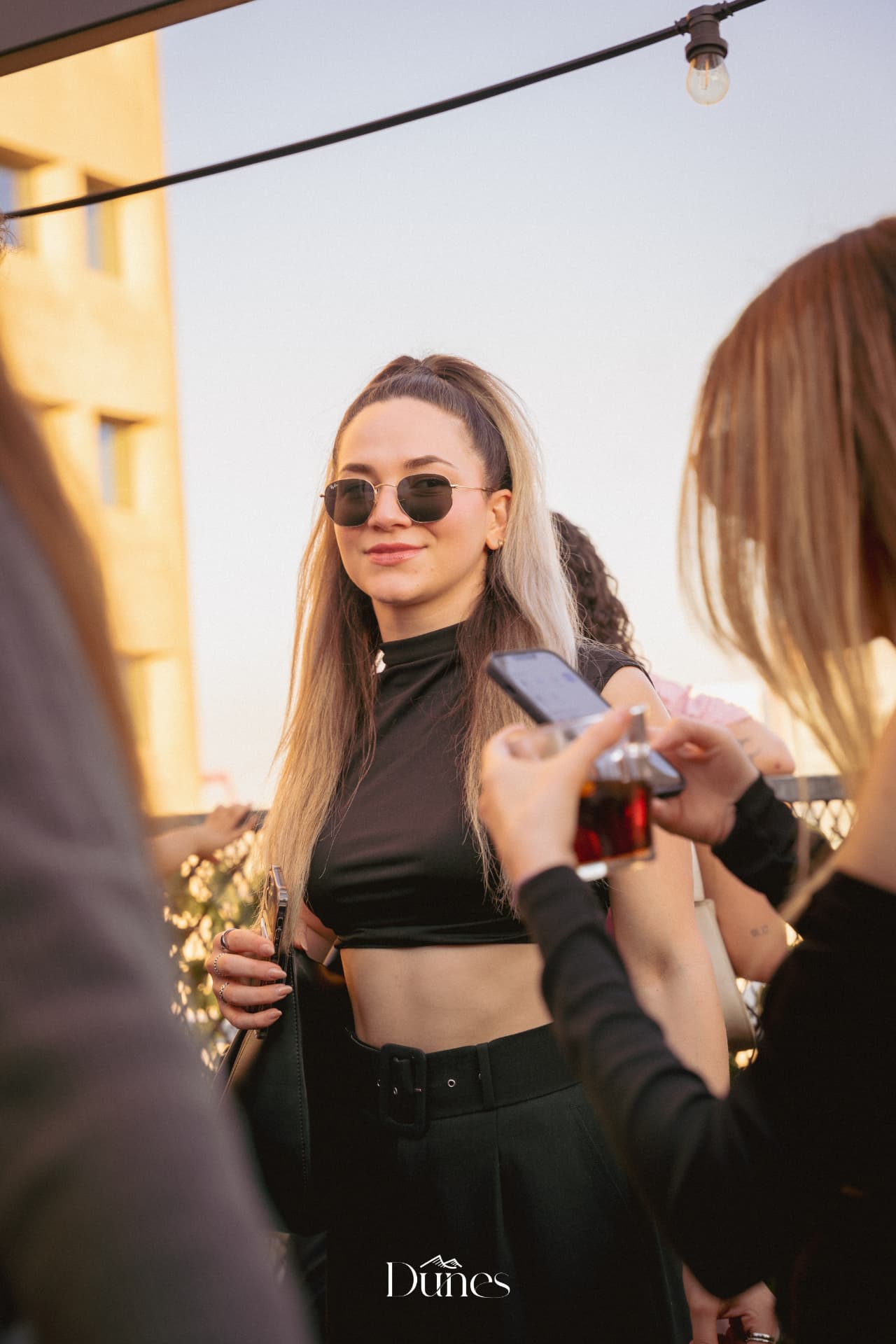 Guest in sunglasses at a Dunes rooftop party at golden hour