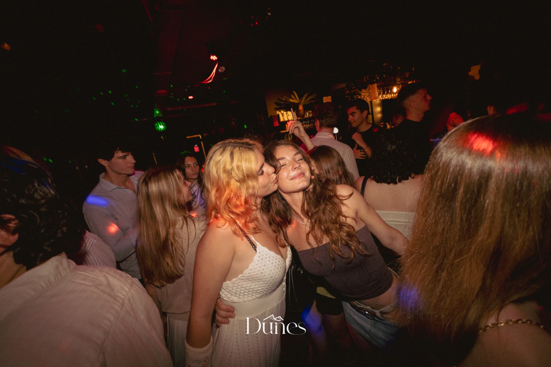 Two friends cheek to cheek on a packed Dunes dancefloor