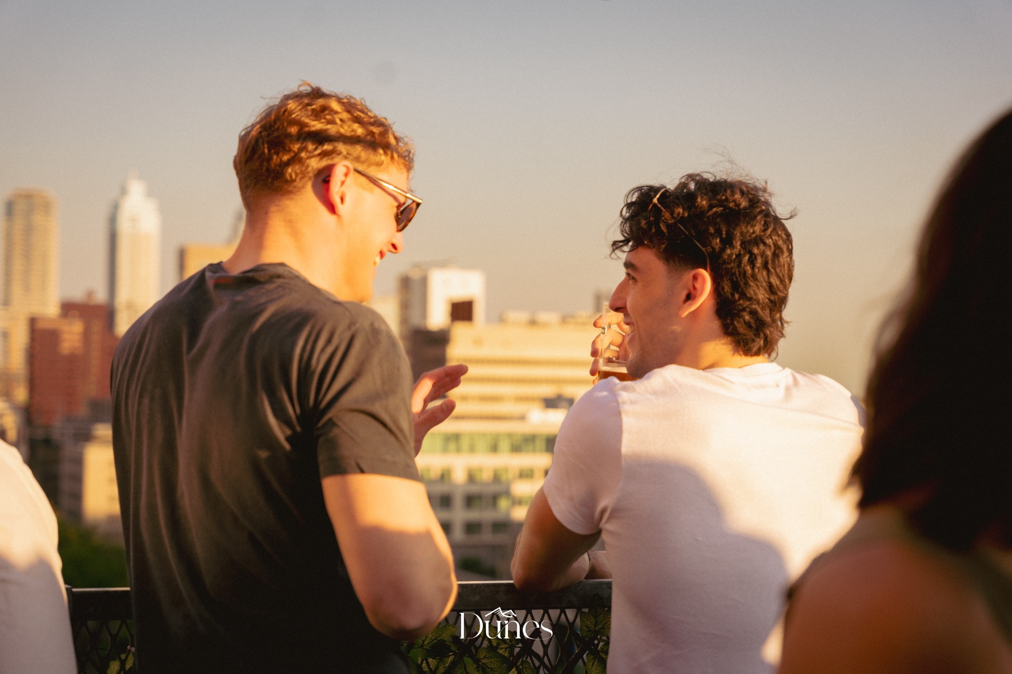 Friends talking at a Dunes rooftop event during golden hour